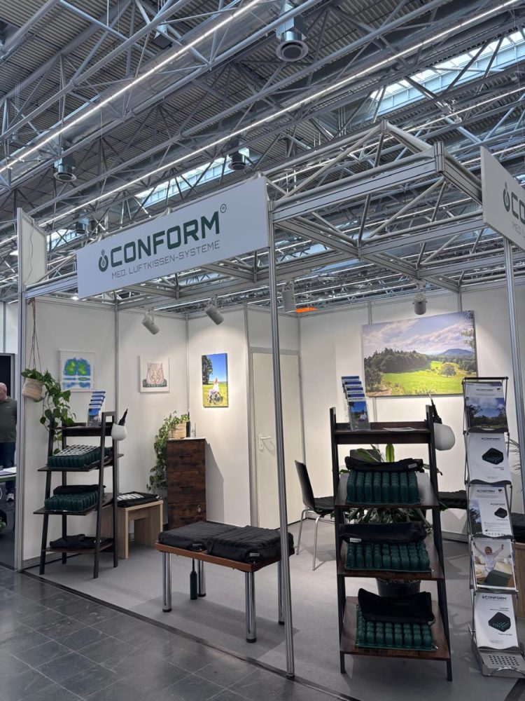 CONFORM®-Messestand A71 in Halle 1 auf der REHACARE 2026 mit Sitzkissen im Regal